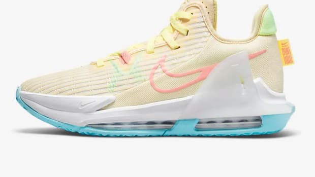 Side view of cream and blue Nike basketball shoe.